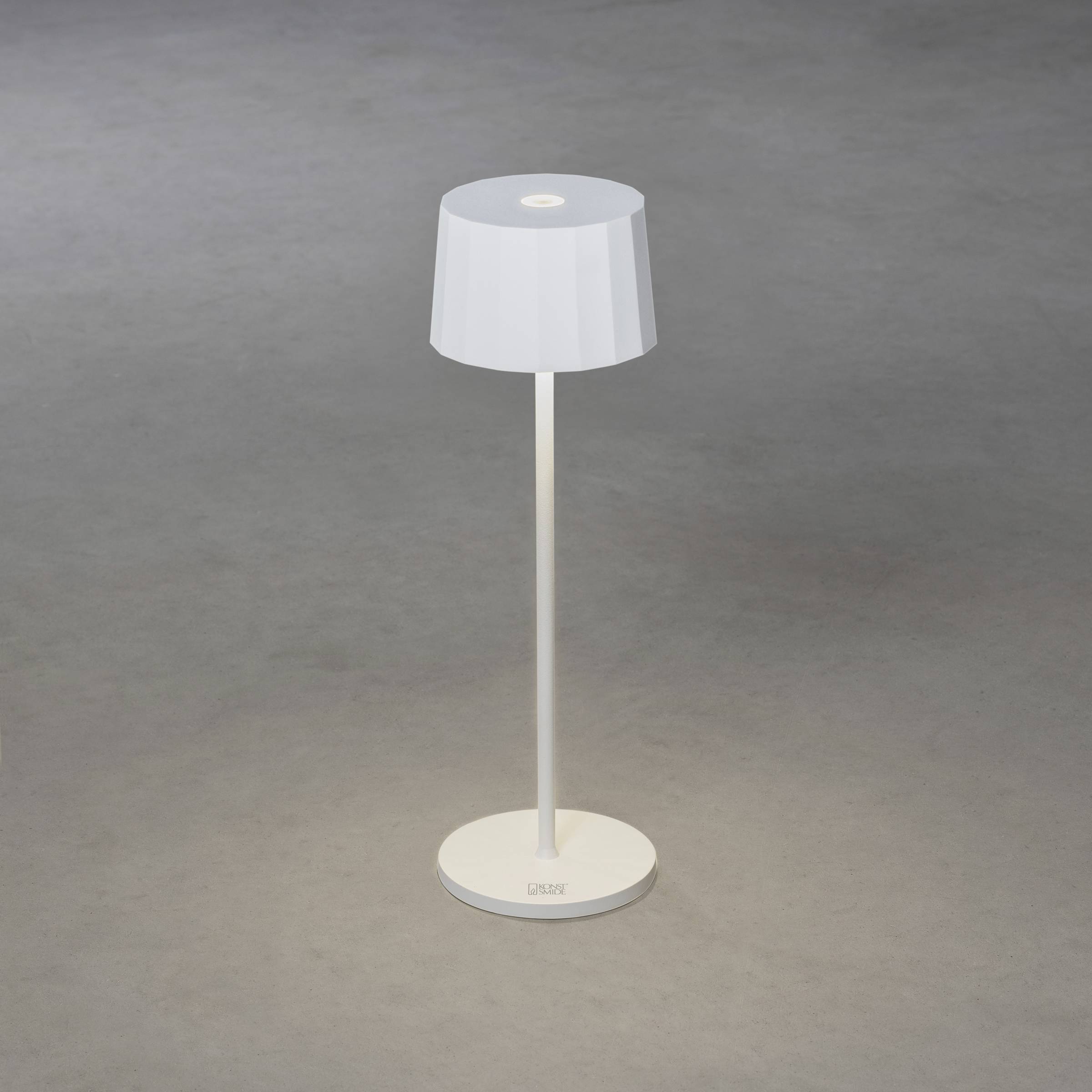 Et moderne gulvlampe med en enkel, hvid skærm og en ret stang står på et gråt gulv.