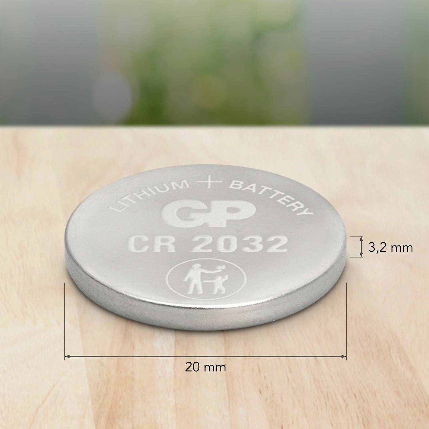 Sølvfarvet knapcellebatteri CR2032 på et træbord, med påskriften 'LITHIUM BATTERY GP CR 2032', diameter 20 mm.