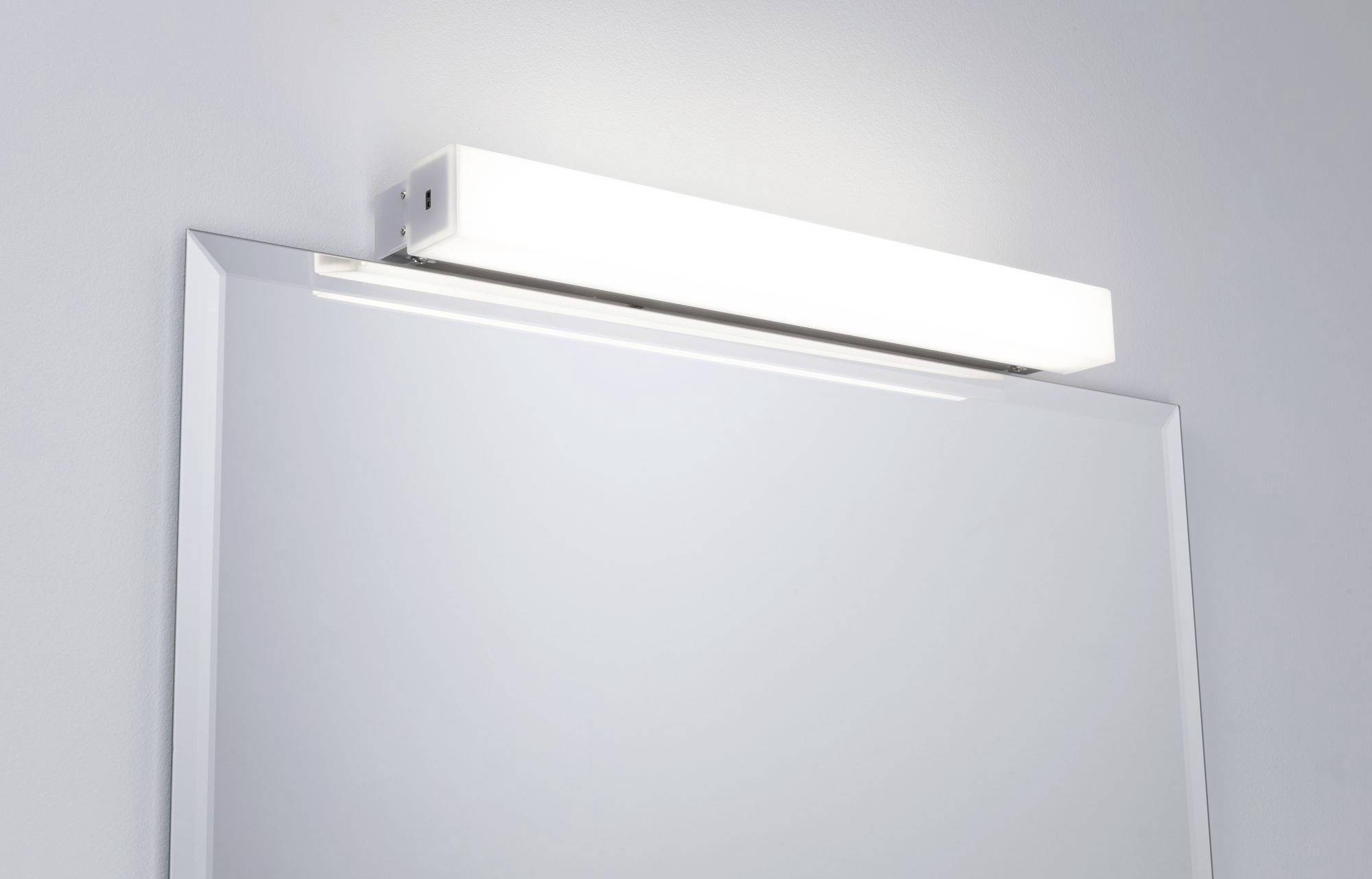 Et rektangulært spejl med en rektangulær, lysende lampe øverst, monteret på en lysegrå væg.