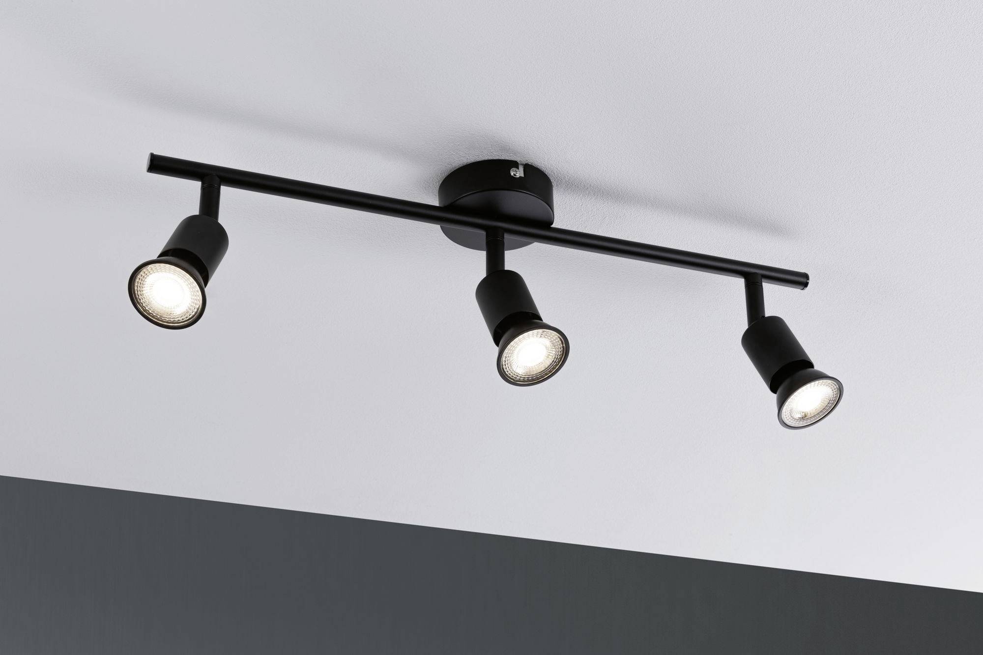 Tre-spotet loftslampe monteret med sorte lampehoved, der peger i forskellige retninger.