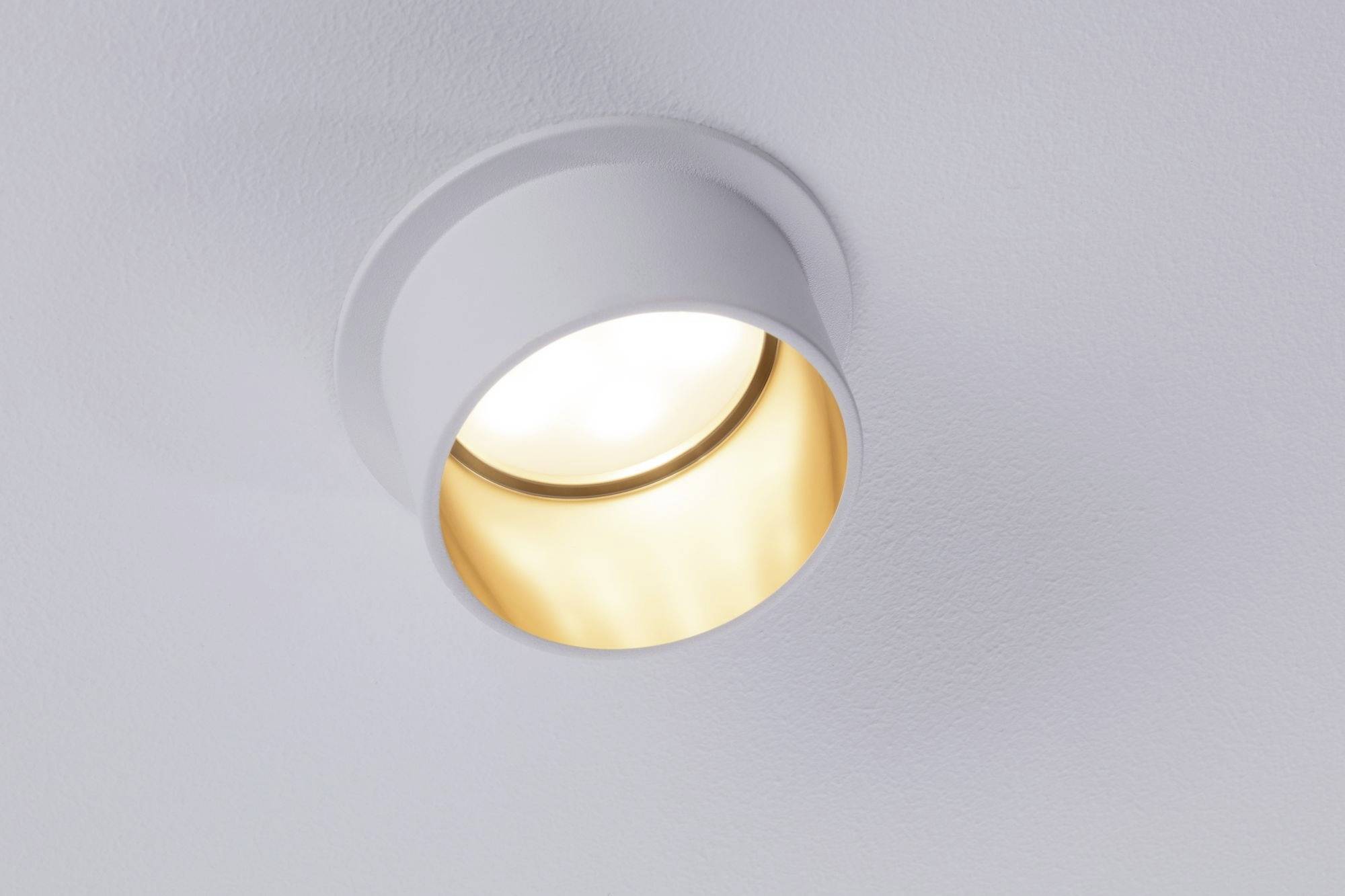 En rund loftslampe afgiver varmt lys, monteret på en hvid lofts flade.