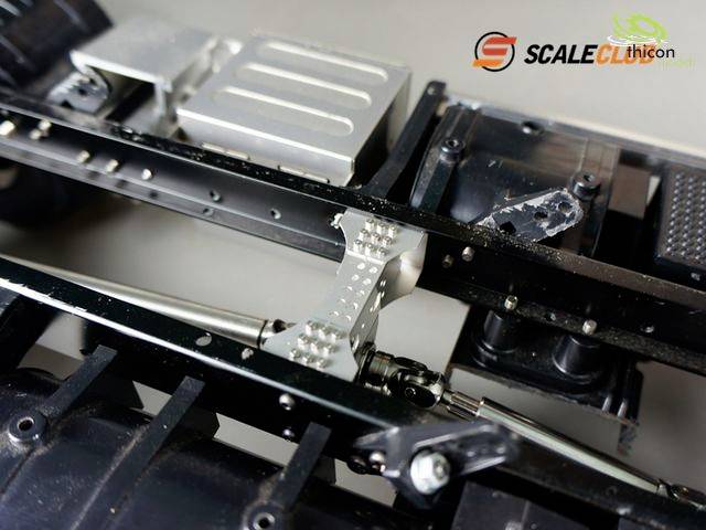 Nærbillede af et modelbilchassis med metal- og plastikkomponenter. Øverst er logoerne for 'Scaleclub' og 'Techicon' synlige.