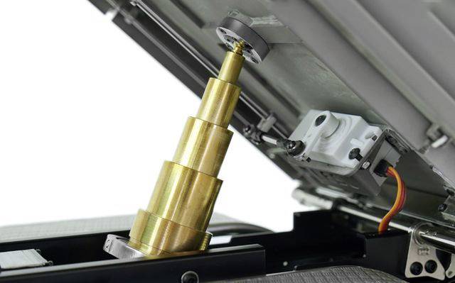 En måleenhed med en udskydelig, guldfarvet cylinder og et kamera er installeret under et åbnet låg.