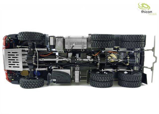 Undervognsvisning af en modelbil, viser chassis og seks store hjul. Komplekse detaljer i køretøjets mekanik er synlige.