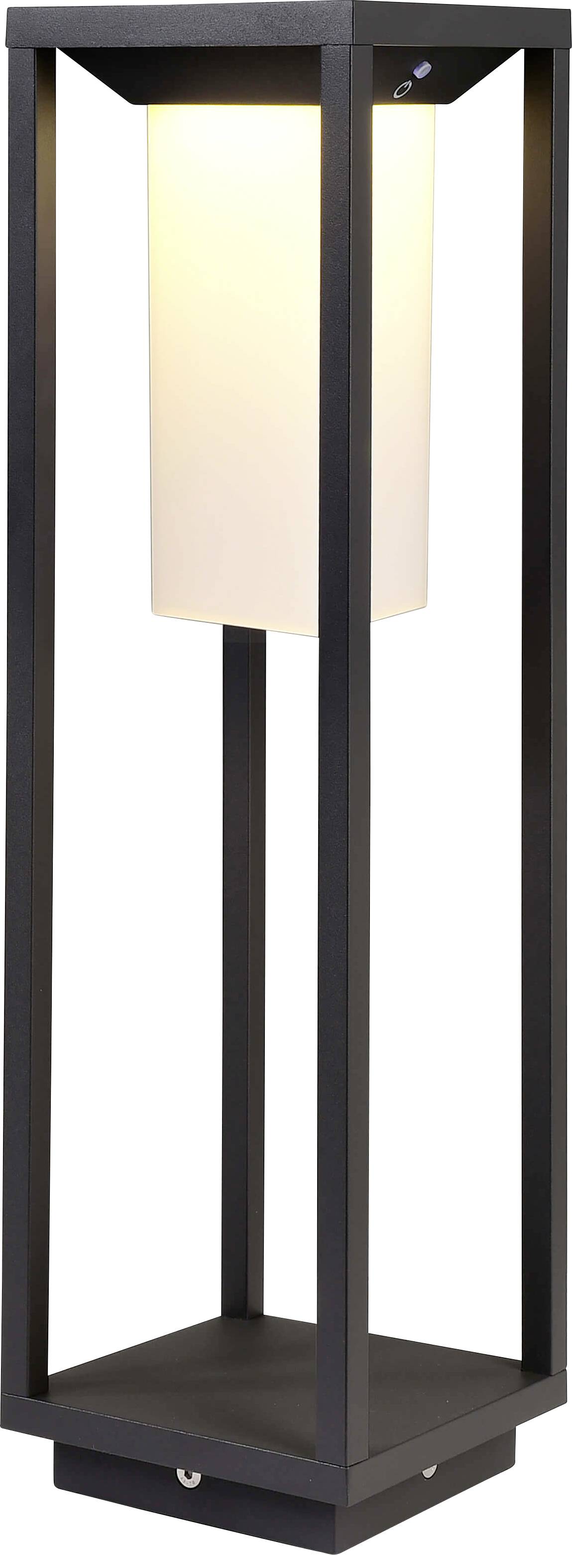 En moderne gulvlampe med sort, kubisk ramme og hvid, cylinderformet lampeskærm, som lyser blødt.