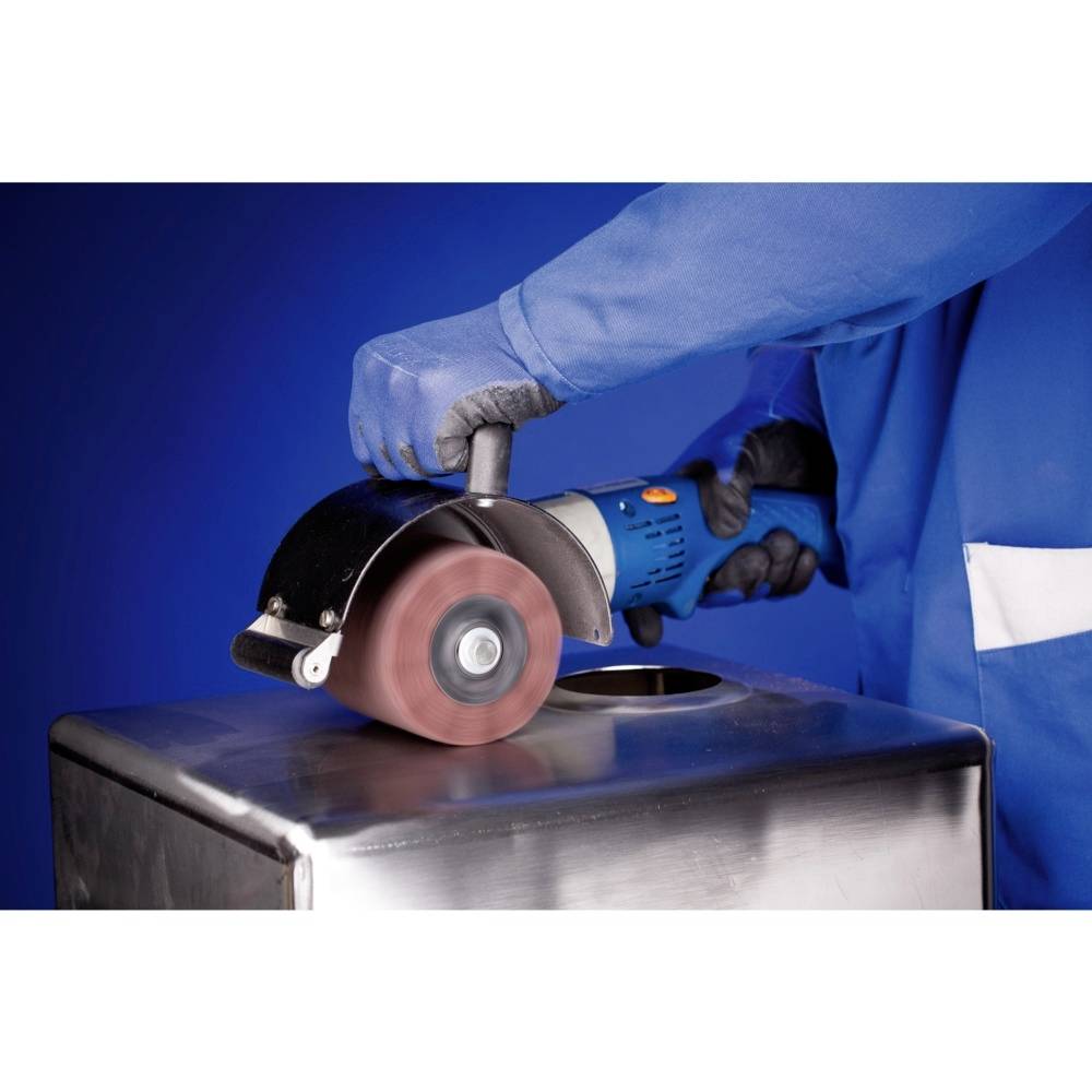 En person i blå beskyttelsesdragt sliber en metaloverflade med en vinkelsliber.