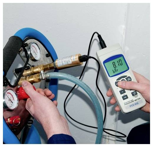 Person der bruger et digitalt trykmanometer til at måle lufttryk på en slange- og ventilsamling, aflæser cirka 8,10 bar