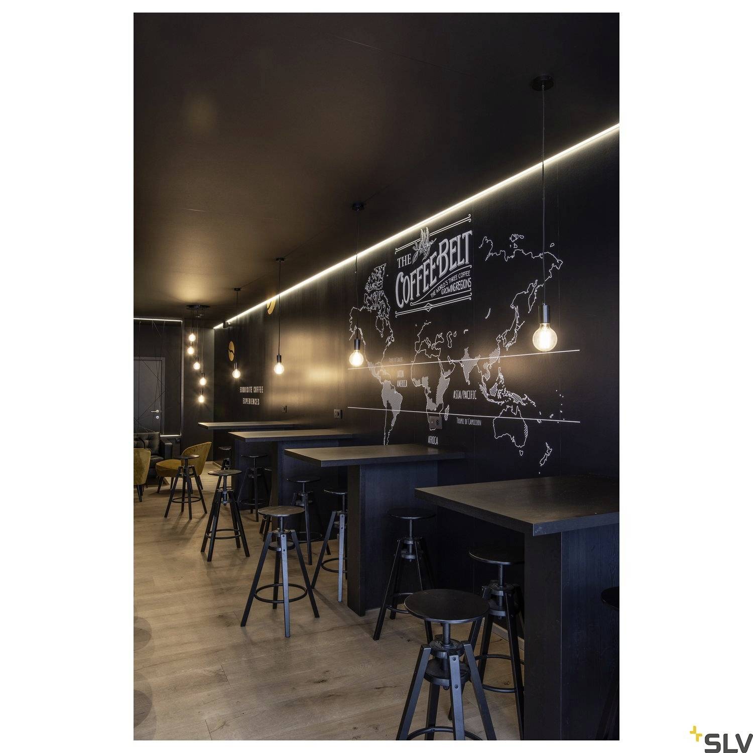 En hyggelig café-indretning med høje borde og barstole. Et verdenskort og logoet 'The Coffee Belt' er ophængt på væggen.