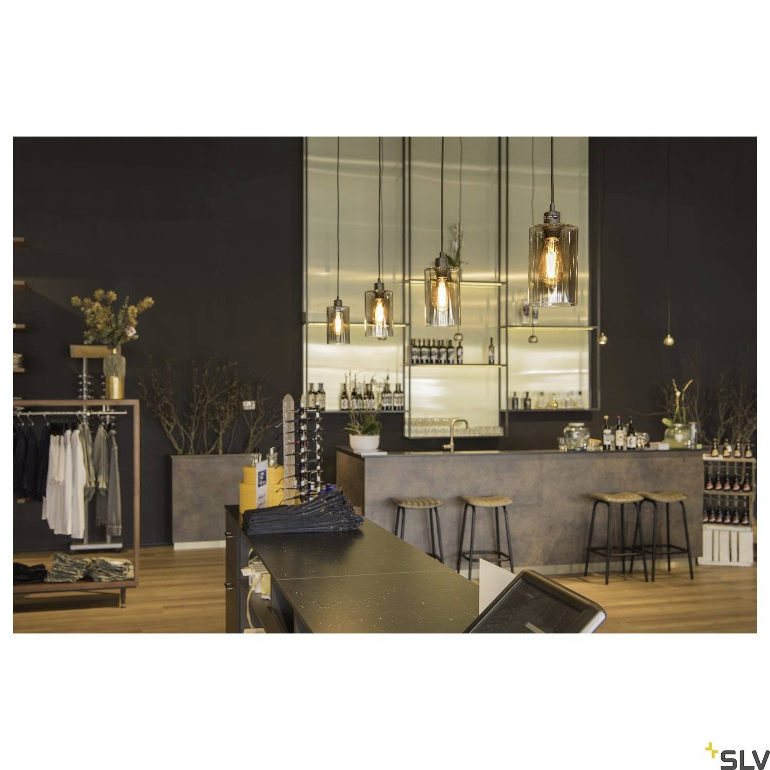 En moderne indrettet bar med trætresen, barstole og dekorative pendullamper; i baggrunden hylder med drikkevarer.