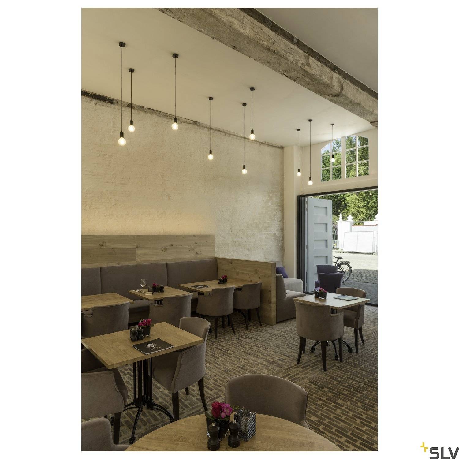 En café med moderne indretning, tréborde og polstrede stole. I baggrunden en åben dør med udsigt udadtil.