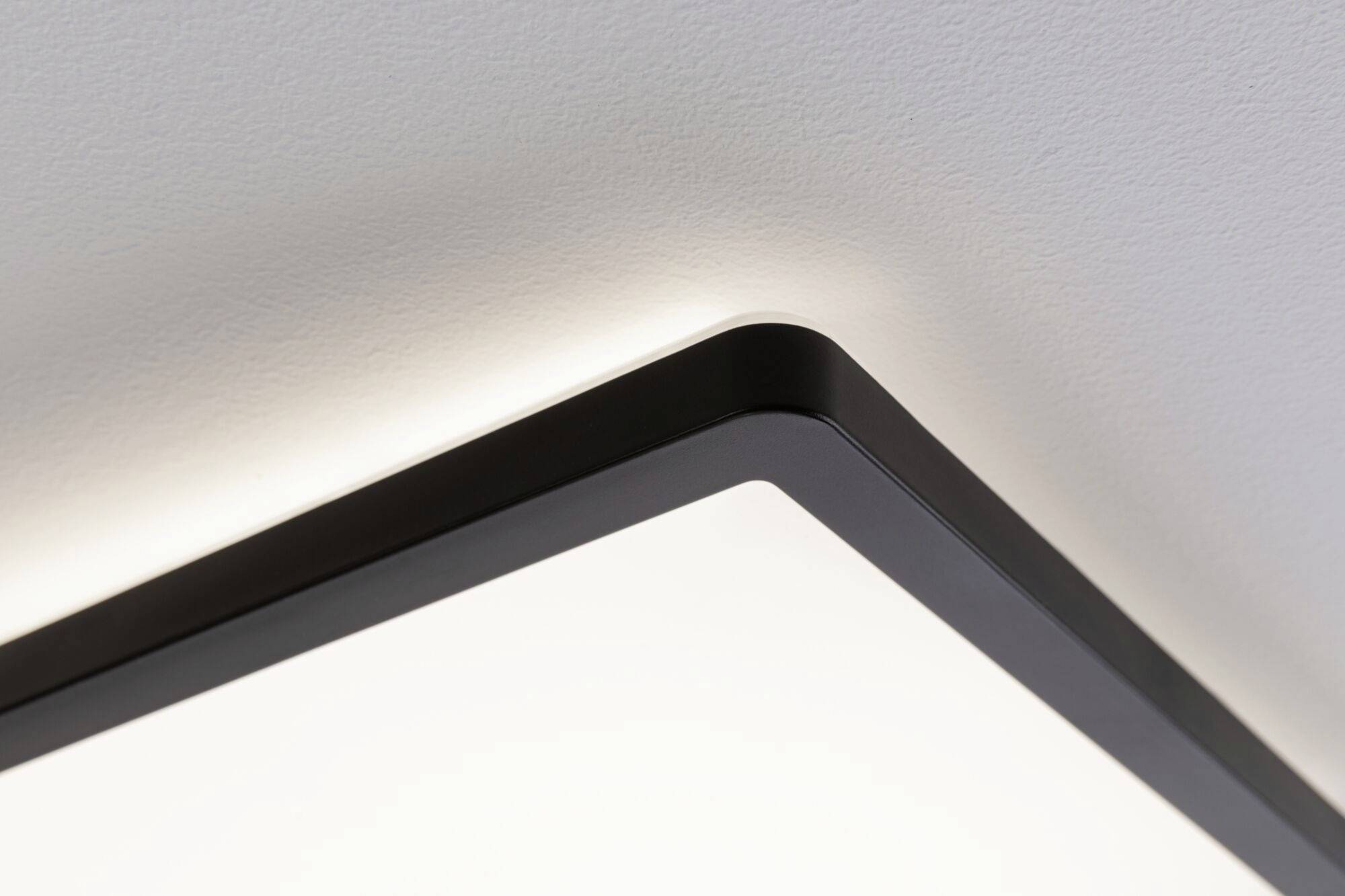 Kantet loftslampe, der lyser på en hvid lofteflade, sørger for blød indirekte belysning.