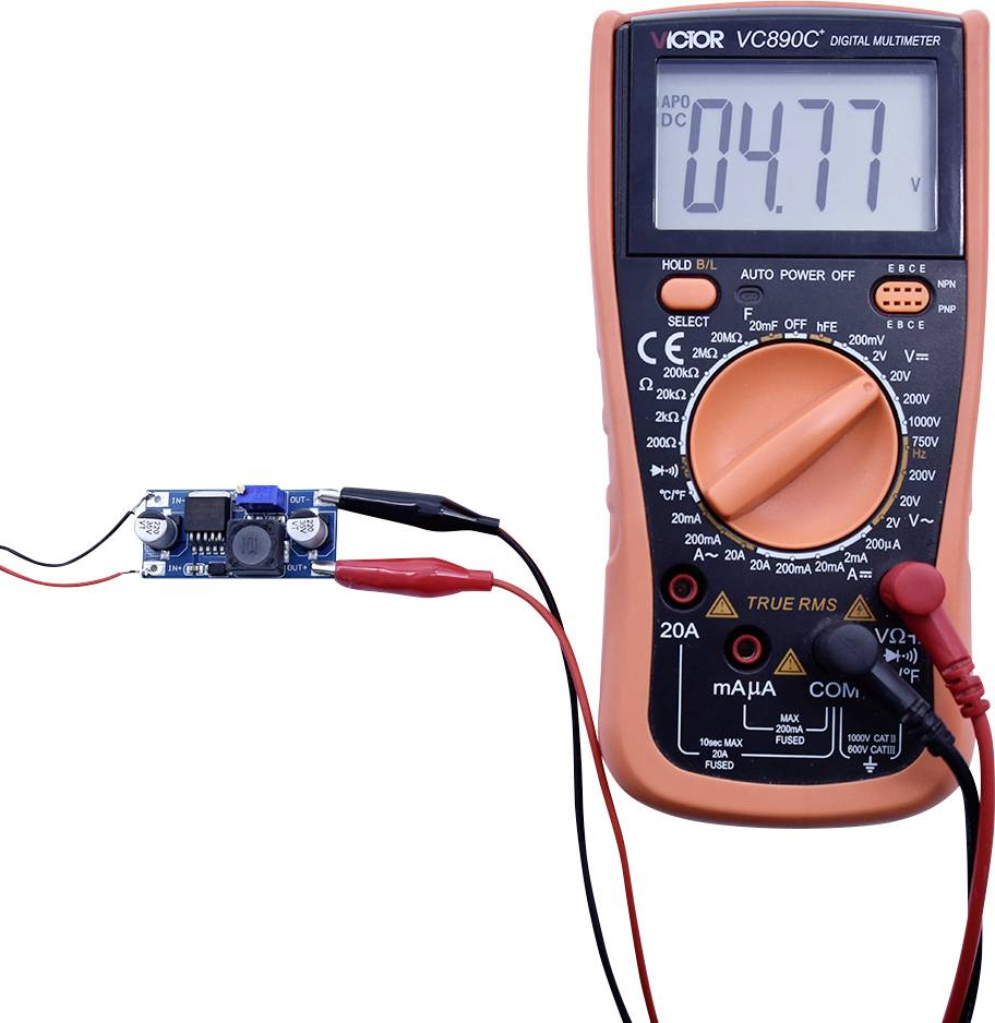 Et digitalt multimeter viser '4.77 V', mens det er tilsluttet et elektronisk modul.