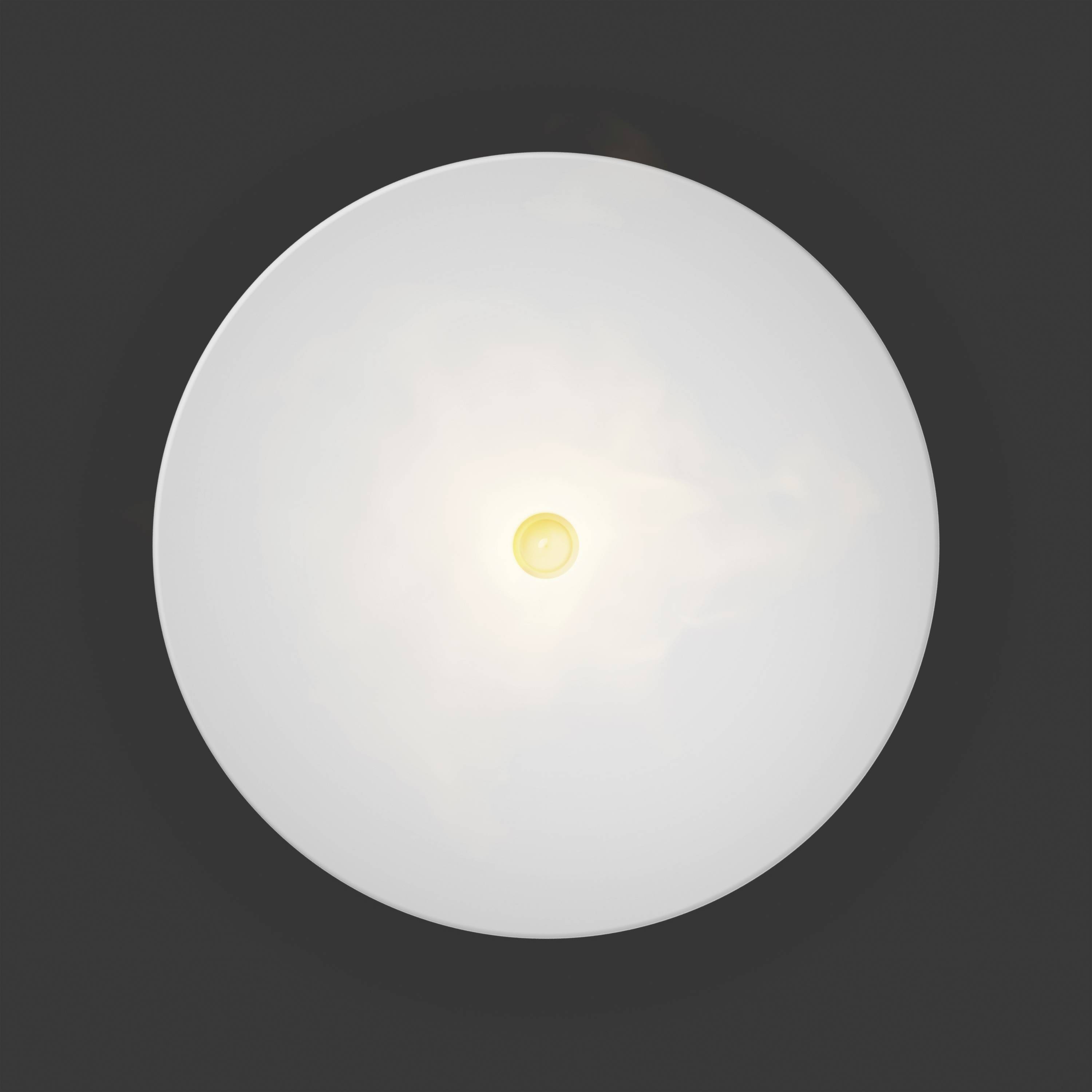 Et rundt loftlampe lyser kraftigt oppefra, foran en mørk baggrund, synlig i midten af billedet.