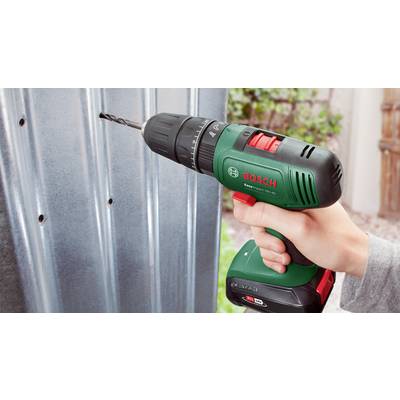 En hånd holder en Bosch-akku-skruemaskine og borer et hul i et metalark.