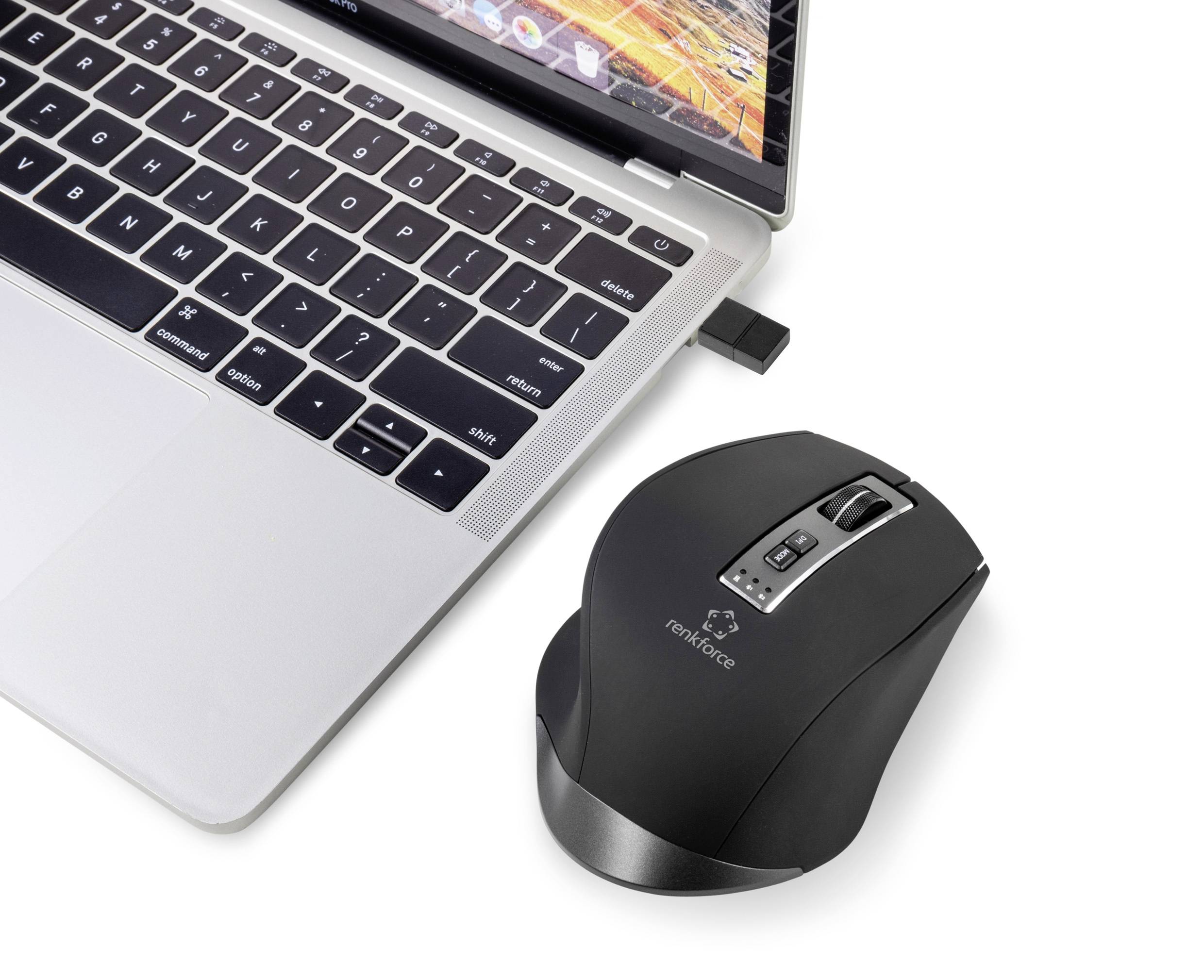 Bærbar computer med tilsluttet trådløs mus på et skrivebord. Musen er ergonomisk og sort med et sølvfarvet detalje.