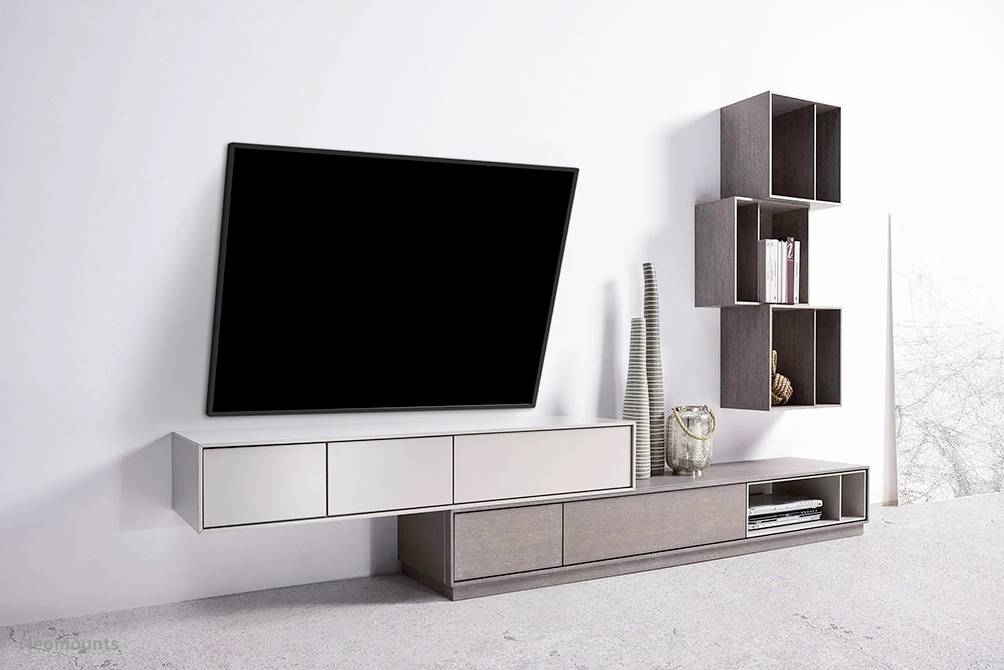 Vægbeklædt opholdsstue med moderne fladskærms-tv, elegante hylder og dekorationsgenstande i minimalistisk indretning.