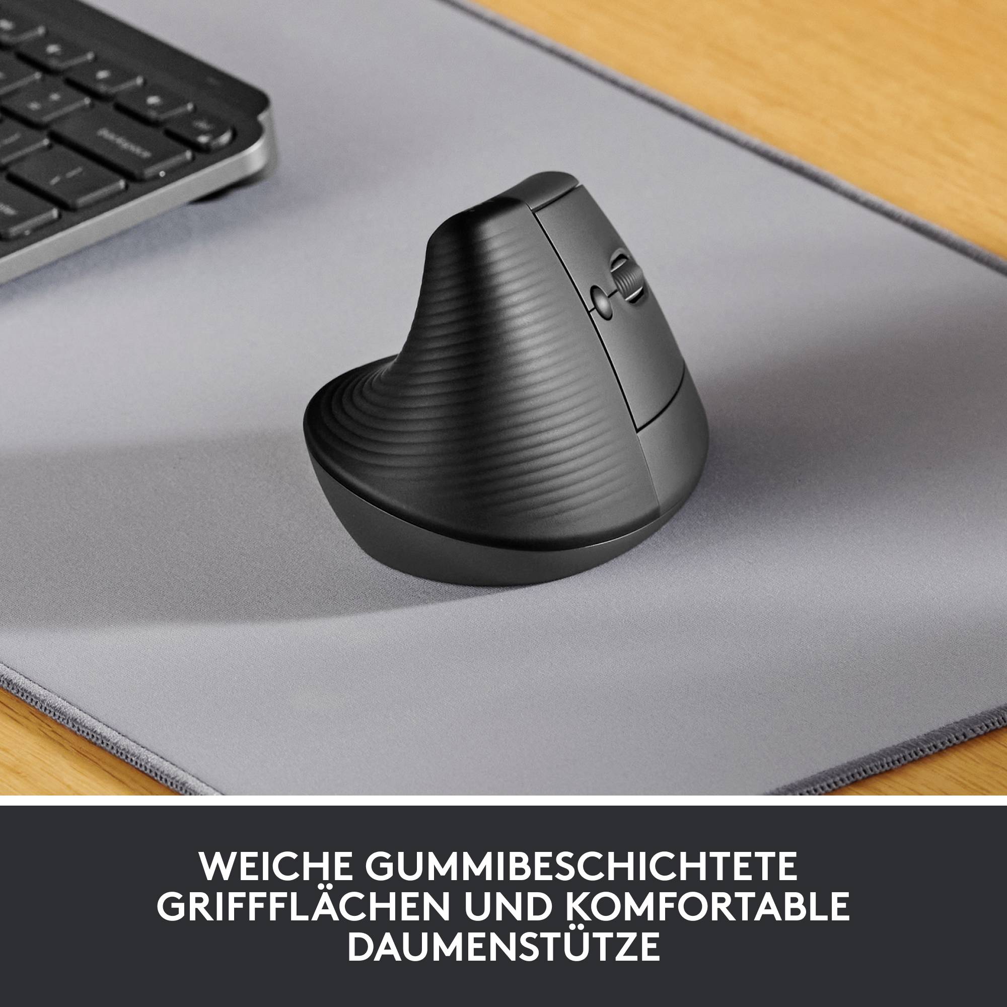 Vertikal mus med ergonomisk design på en grå musemåtte ved siden af et computertastatur. Tekst: 'Blød gummibelagt grebsflade og behagelig tommelflidsstøtte'.