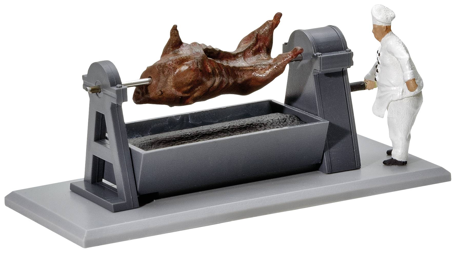 En model af en kok drejer et stegt dyr på en spyd over et rektangulært opsamlingsfad.
