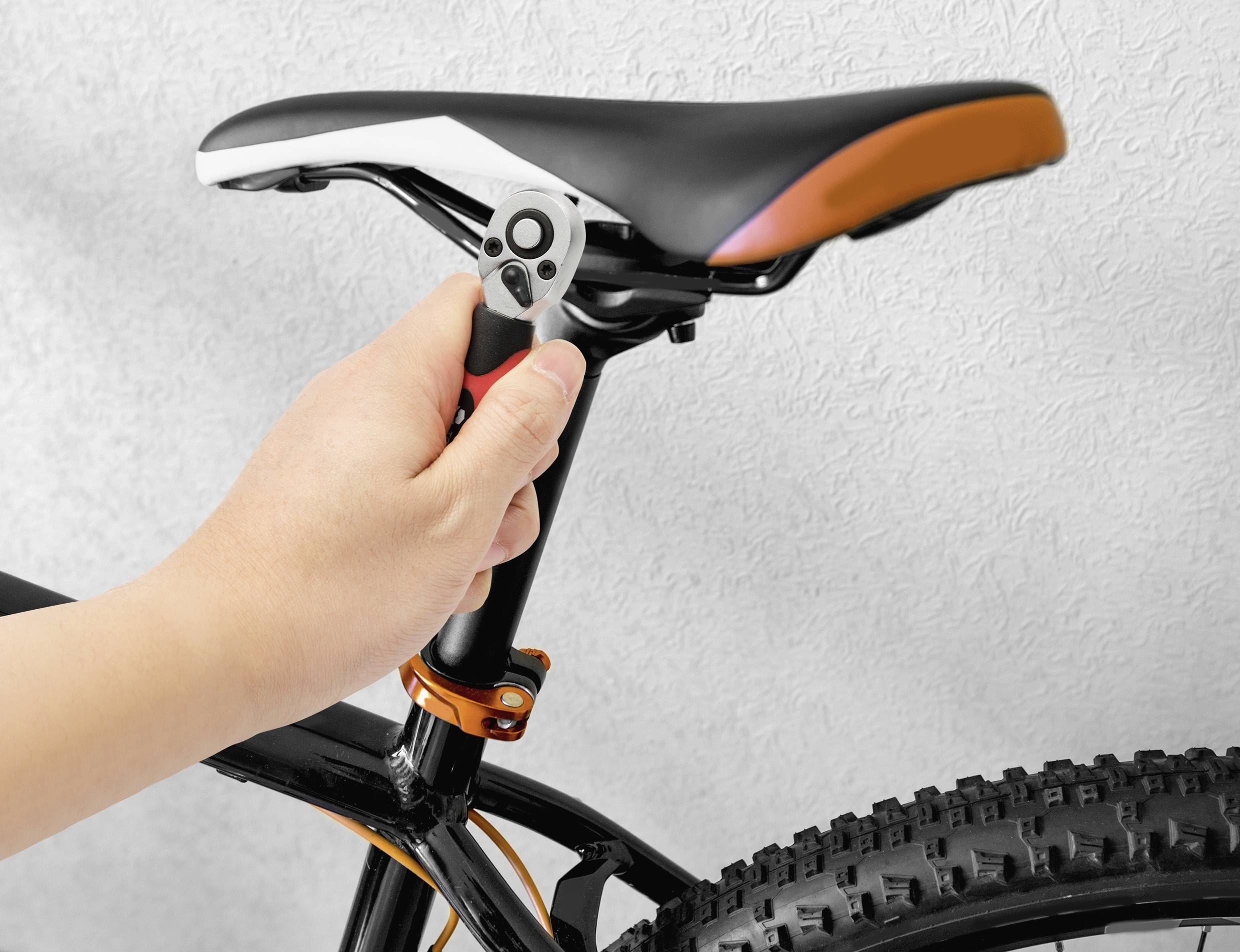 Justerer cykelsadel manuelt med en skruenøgle.