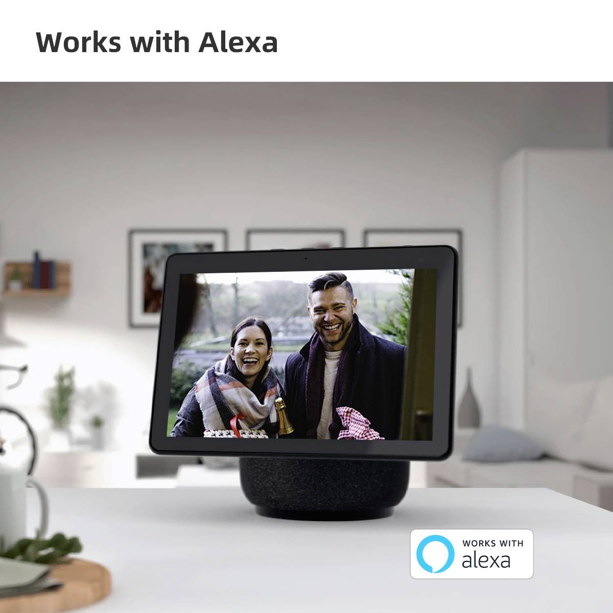 En intelligent højtaler på et bord viser et display med et glad par og 'Fungerer med Alexa'-tekst og logo.