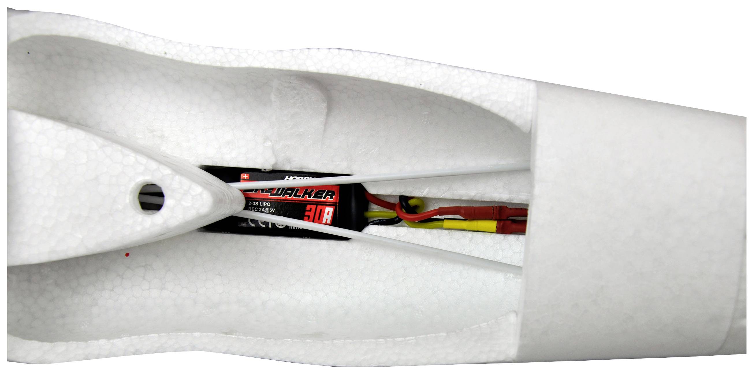 Indvendig side af en modelflyvningsfly-krop lavet af hvid skum. En elektronisk komponent med kabler er installeret.