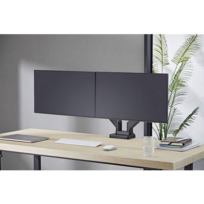 Et moderne skrivebord med to store computerskærme, et tastatur, en bærbar computer og bøger. I baggrunden en plante.