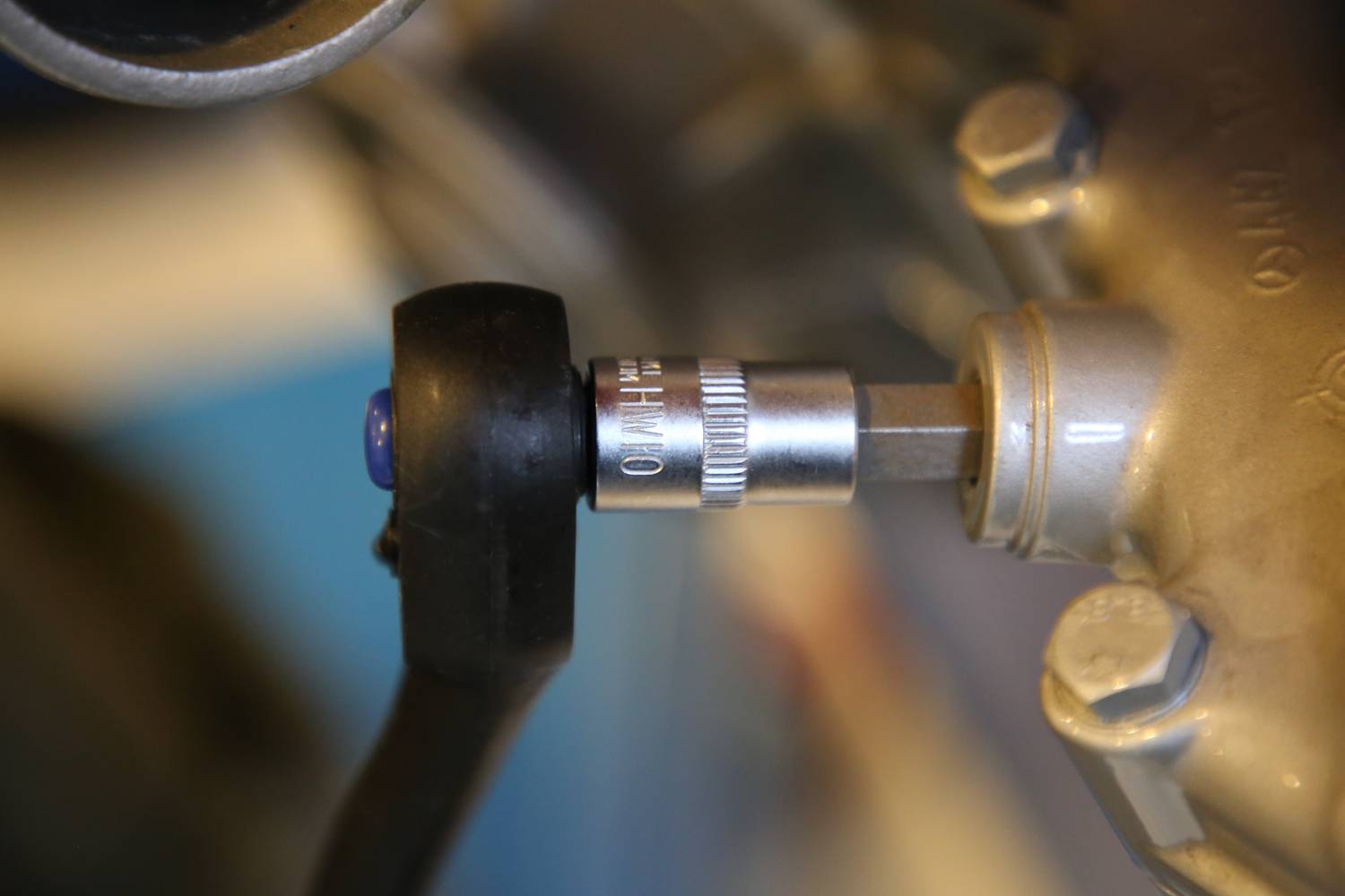 Nærbillede af en momentnøgle, der spænder en skrue fast på en metalgenstand, muligvis en del af en motor.