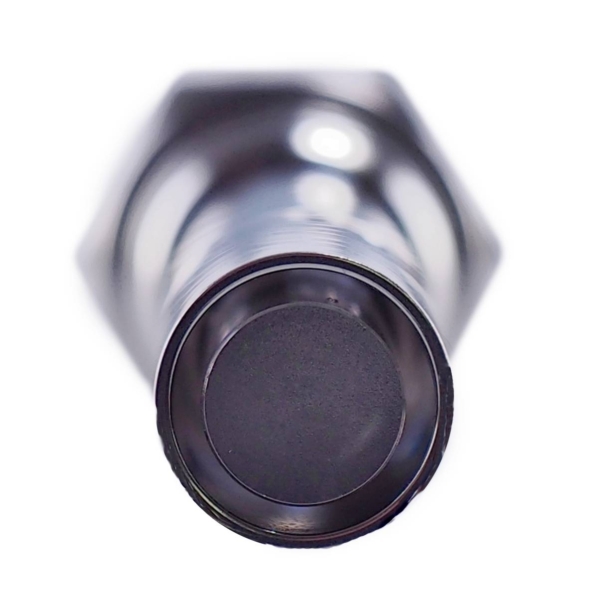 Et sølvfarvet cylinderformet metalgenstand, muligvis en bolt eller et ventil. Set oppefra på den flade ende.