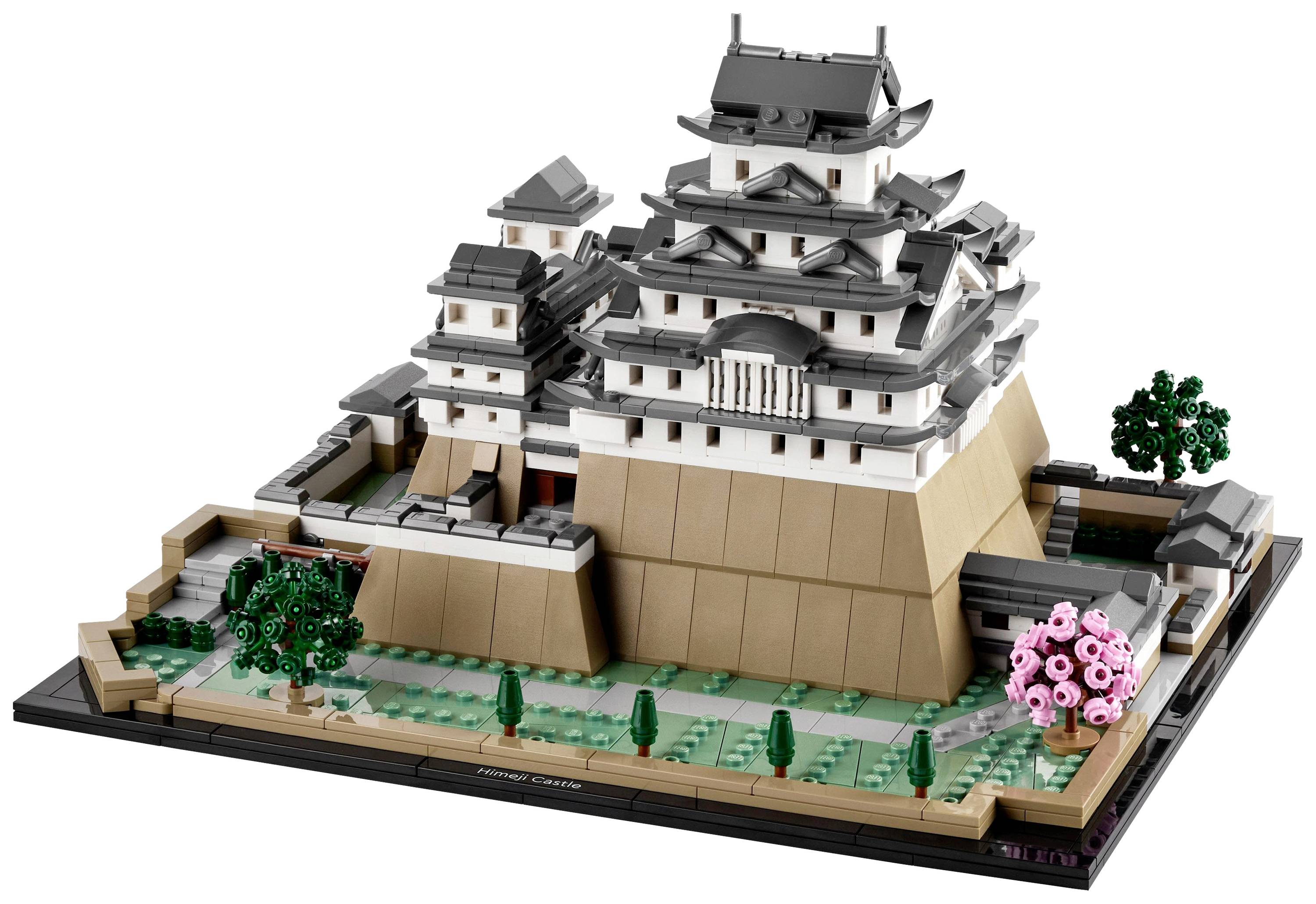 En detaljeret LEGO-model af en japansk borg på en piedestal, omgivet af træer og en lille mur.