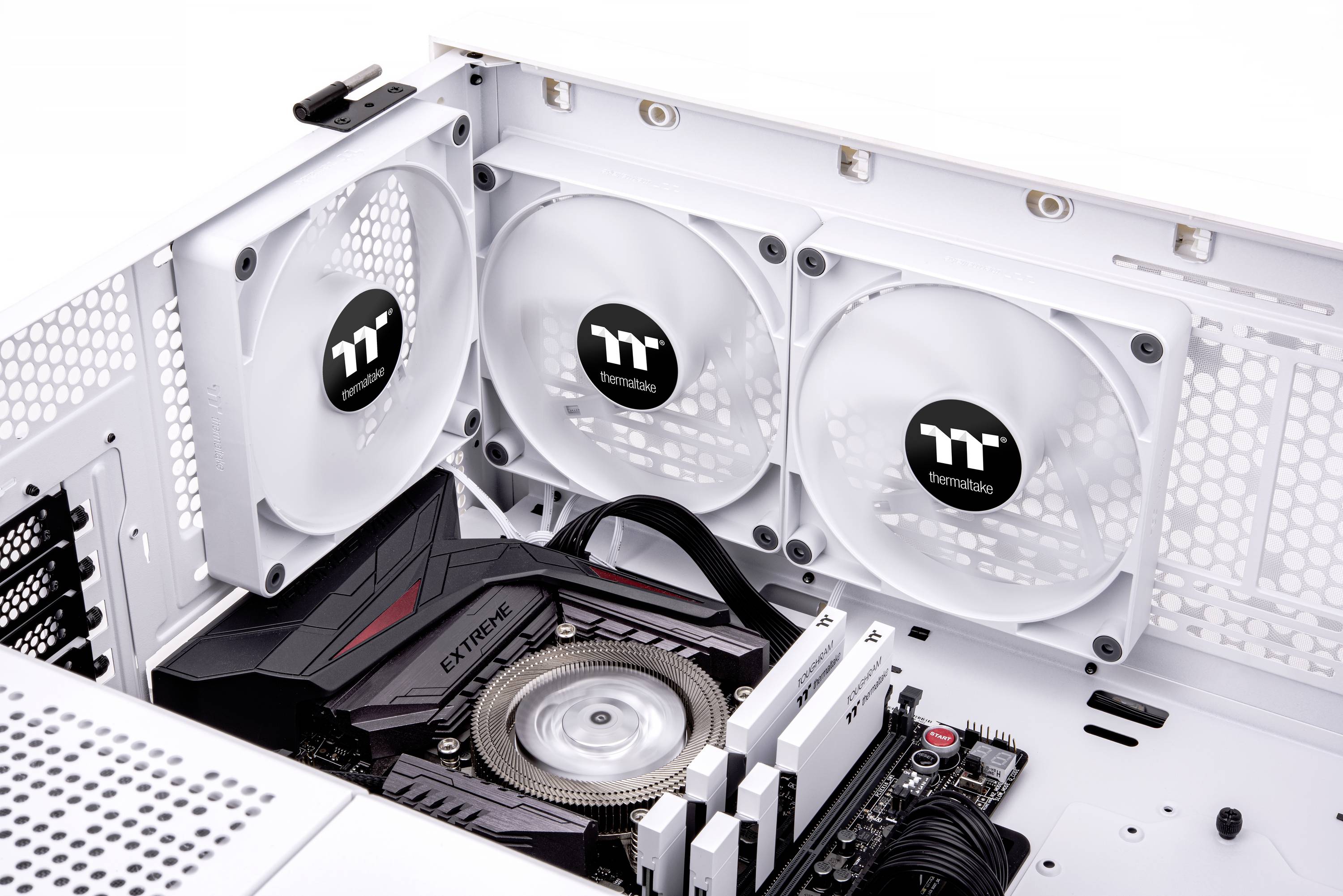 Tre hvide blæsere i et åbent computeretui. Herunder et grafikkort og processor-køleren på et bundkort.