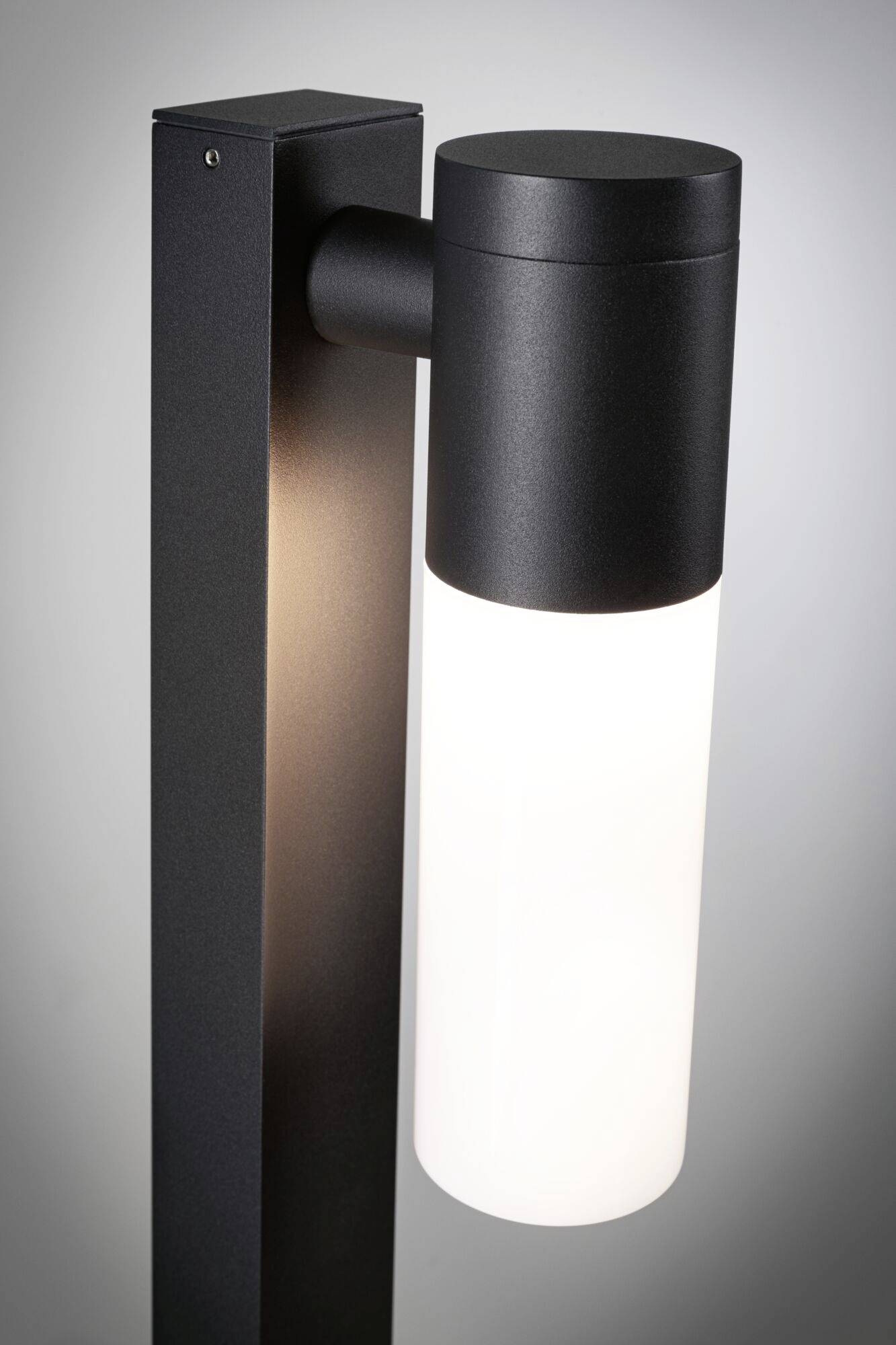 Moderne sort gulvlampe med cylindrisk, halvtransparent lampeskærm, der udsender diffust lys.
