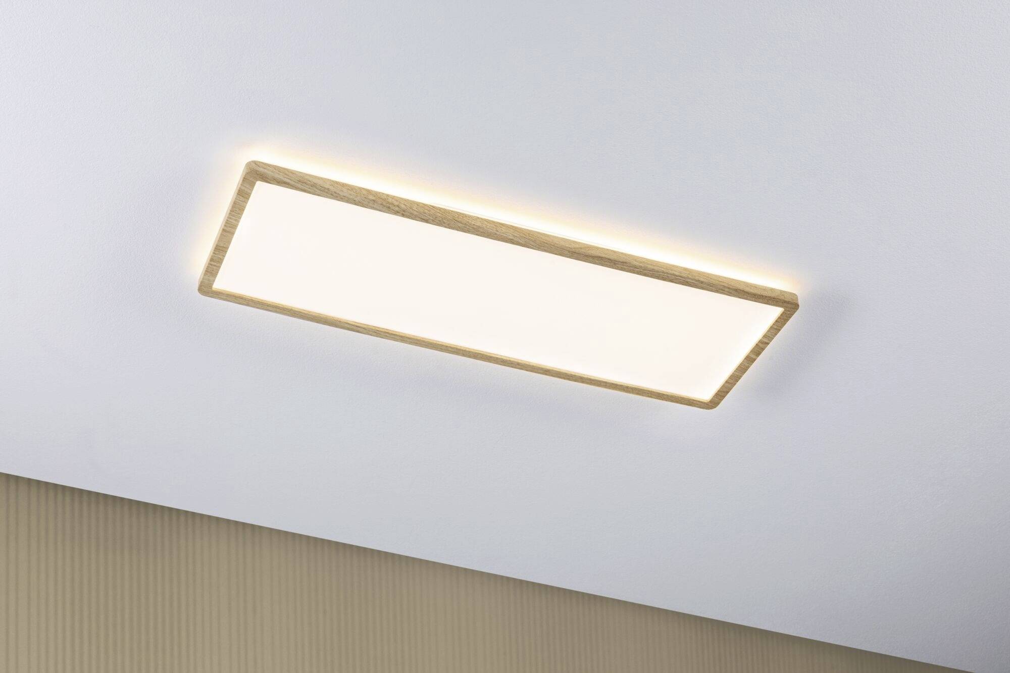 Rektangulær loftslampe med træramme på en hvid lofts, som lyser blødt og sørger for ensartet belysning i rummet.