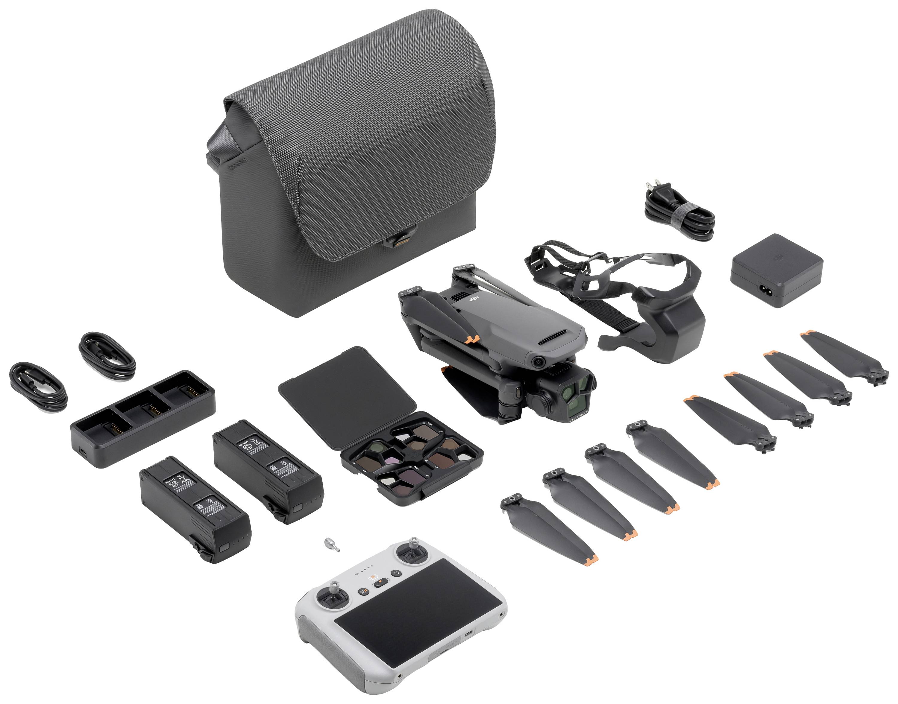 Drone-kit med foldbar drone, fjernbetjening, batterier, propeller, opladere, kabler og bæretaske på hvid baggrund.