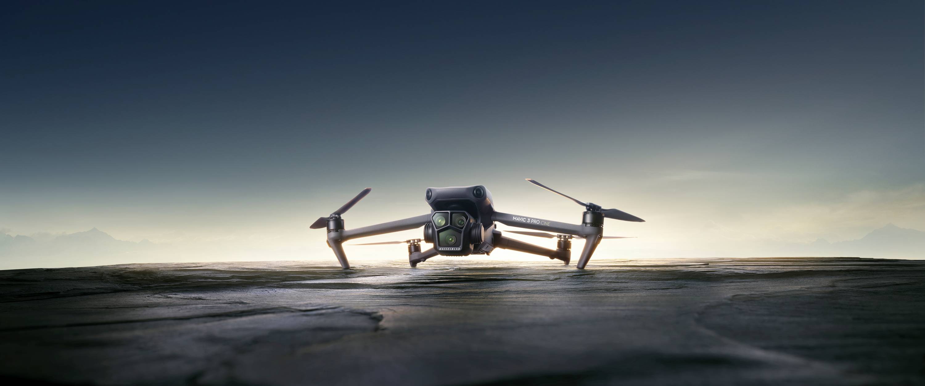 En drone svæver over en stenflade foran en klar himmel. Den er centralt placeret i billedet og ser ud til at optage.