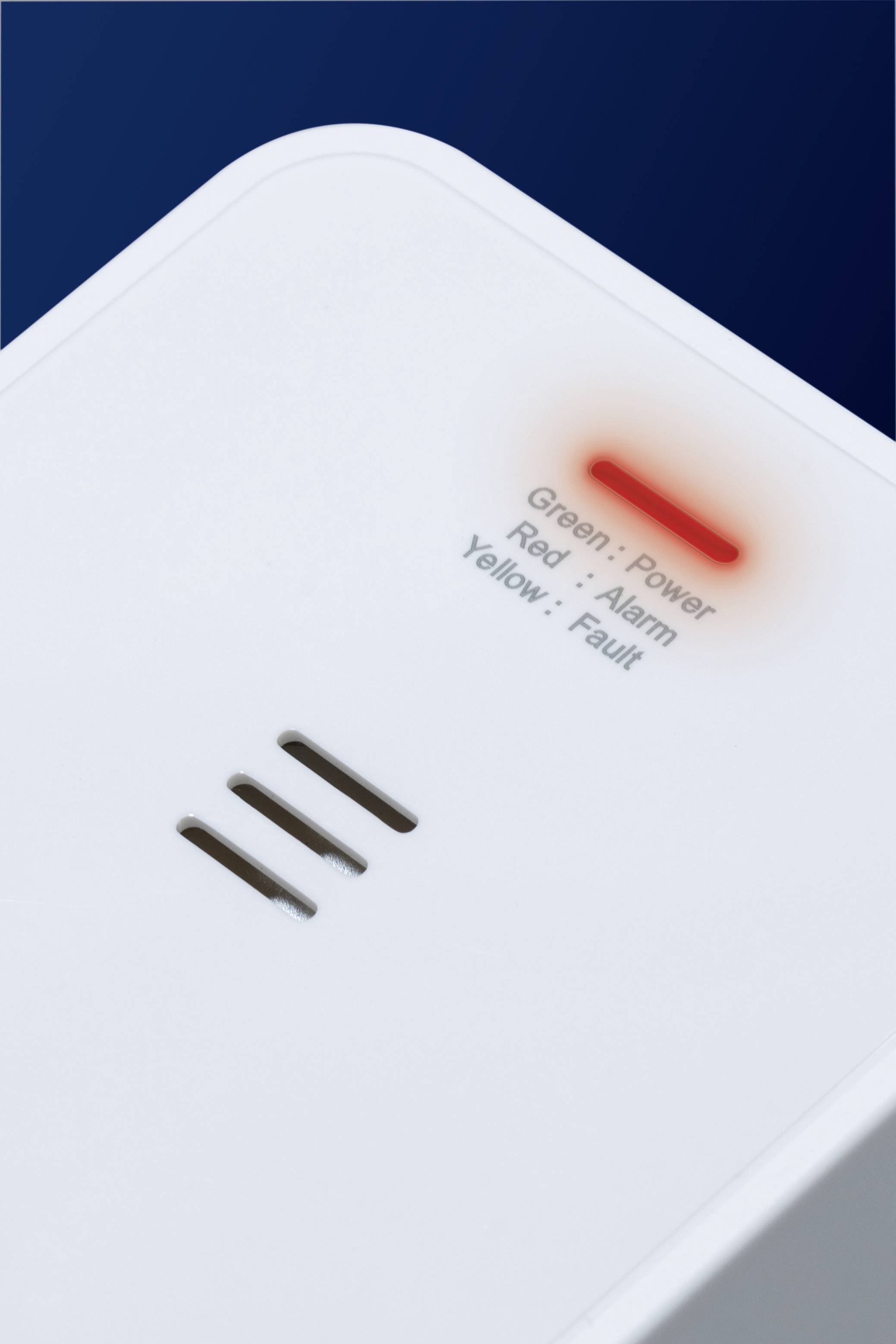 En hvid elektronisk enhed med lamper: Grøn for 'Strøm', Rød for 'Alarm', Gul for 'Fejl'. Den røde lampe er aktiveret.