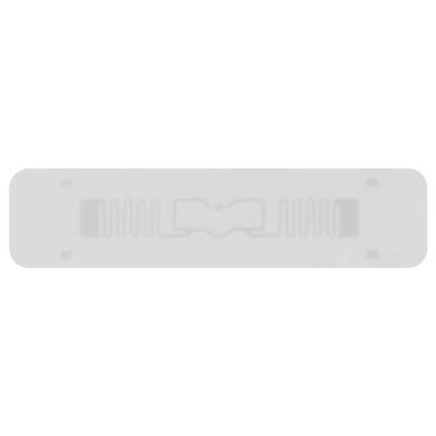 En rektangulær gennemsigtig klistermærke med indlejret RFID-antenne og mikrochip, foran lys baggrund.