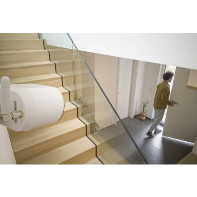 En person åbner hoveddøren, mens en sikkerhedsenhed er installeret i forgrunden. Trappen er lavet af træ med et glasrækværk.