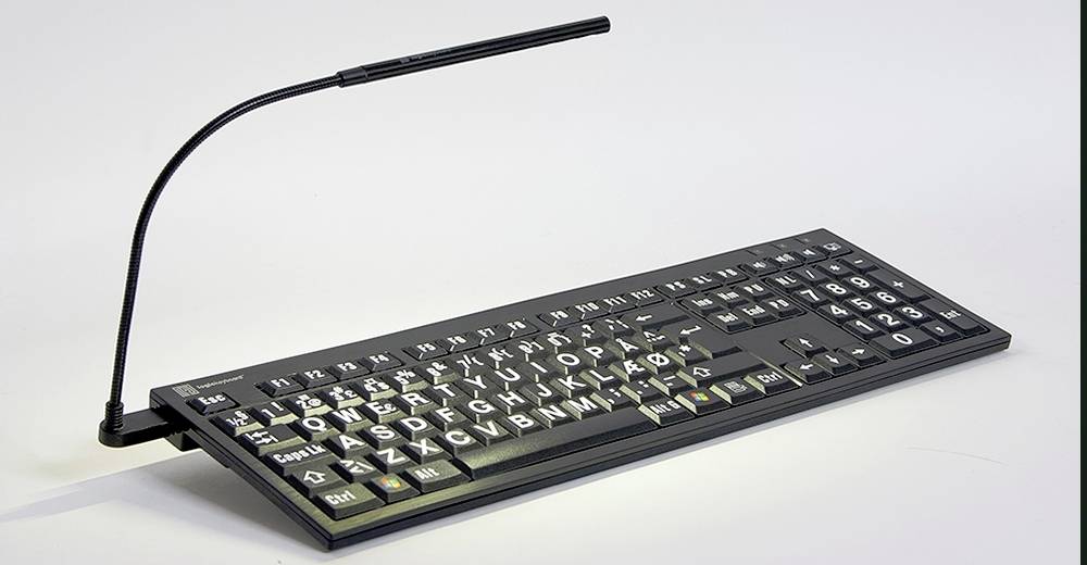 Et sort tastatur med store hvide bogstaver og symboler, udstyret med en fleksibel lampe for bedre synlighed.