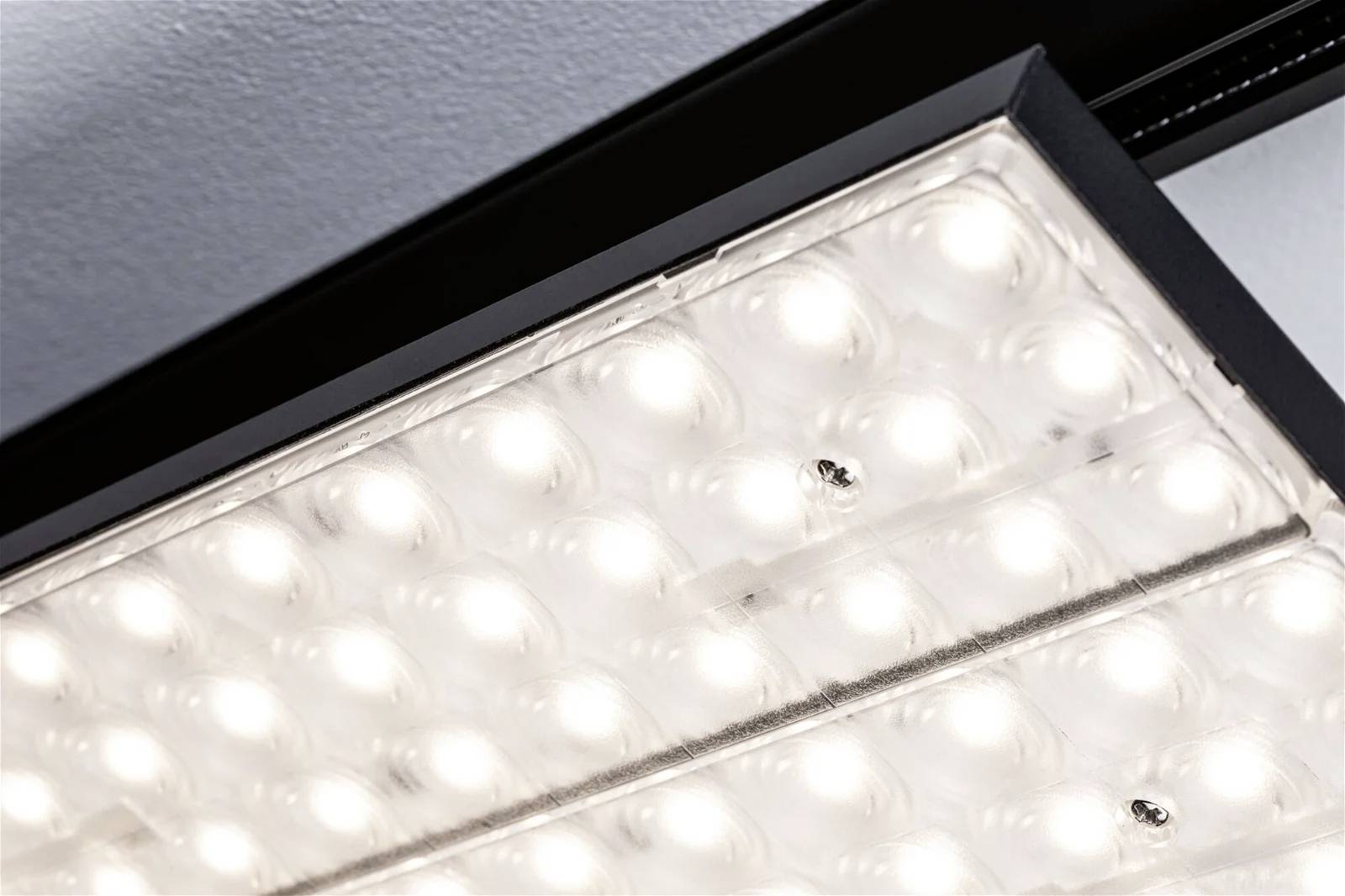 En stor, erhvervsmæssigt anvendt LED-armatur, der er monteret i loftet, lyser op nedefra. Armaturen har et rastermønster.