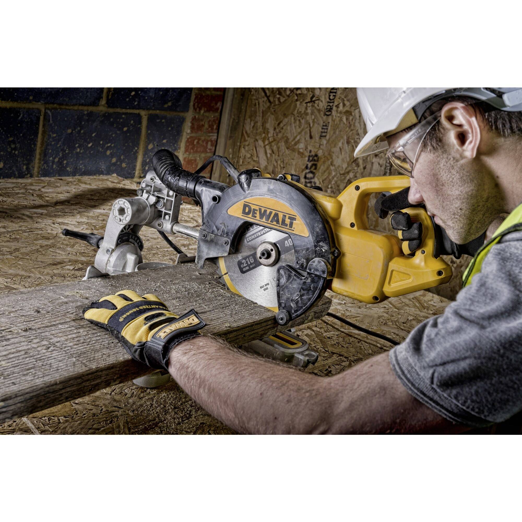 En arbejder, der skærer et stykke træ med en gul rundsav, bærer sikkerhedshjelm og handsker. Saven er af mærket DeWalt.