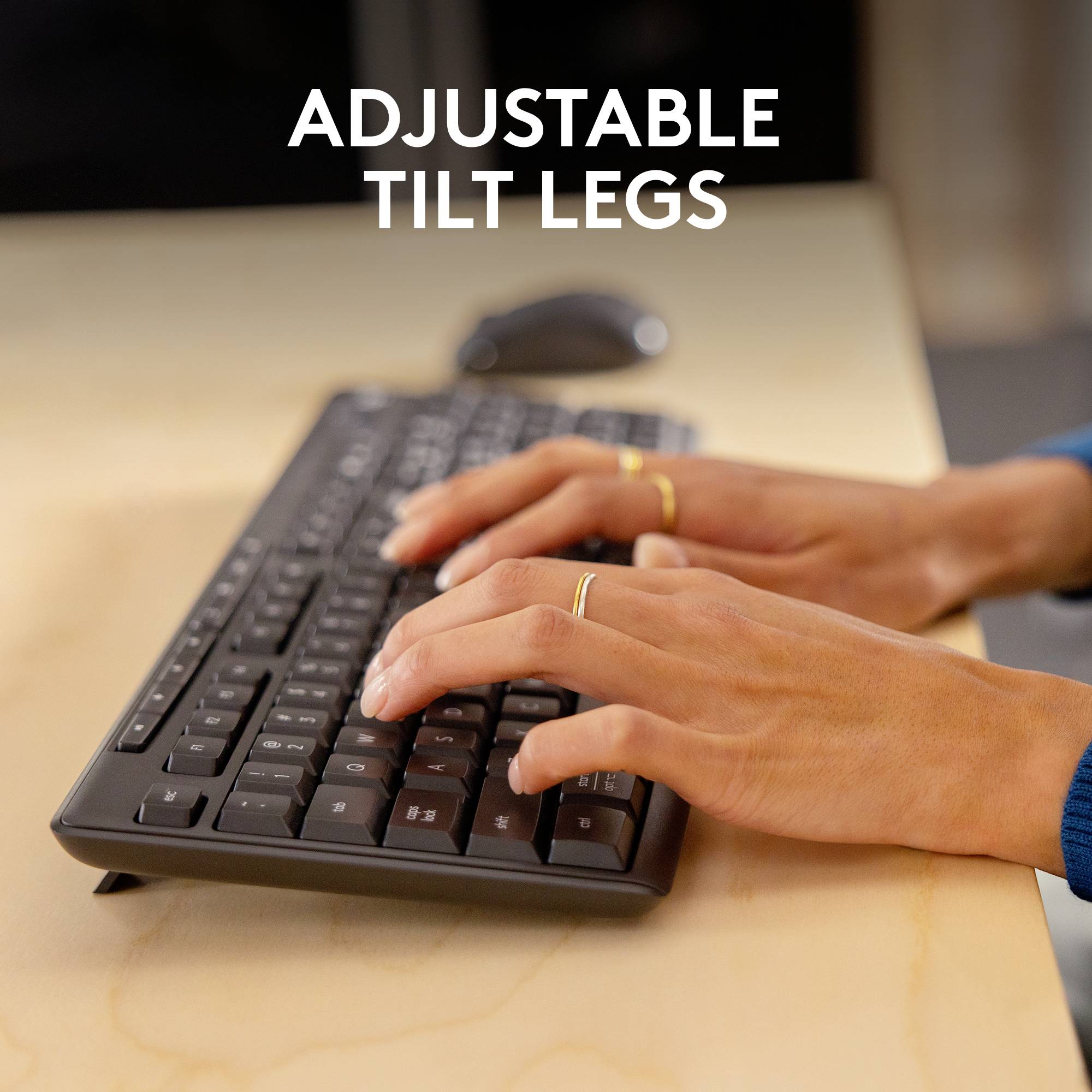 To hænder skriver på et computertastatur. Teksten 'Justerbare tastaturfødder' antyder en funktion ved tastaturet.