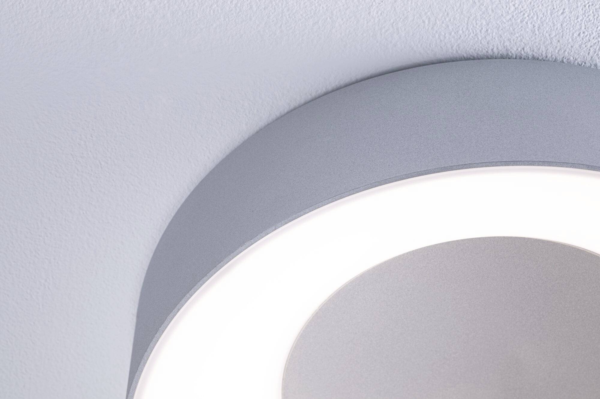 En rund, moderne loftslampe udsender blødt lys på en hvid loft, hvilket skaber en rolig atmosfære.