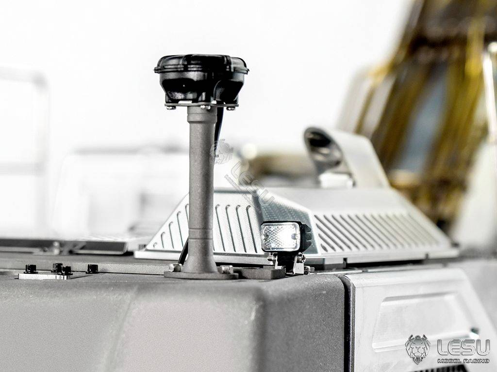 Nærbillede af en modelkøretøjsantenne på taget, med en lille sidespejl og delvist udsyn mod Lesu-logoet.