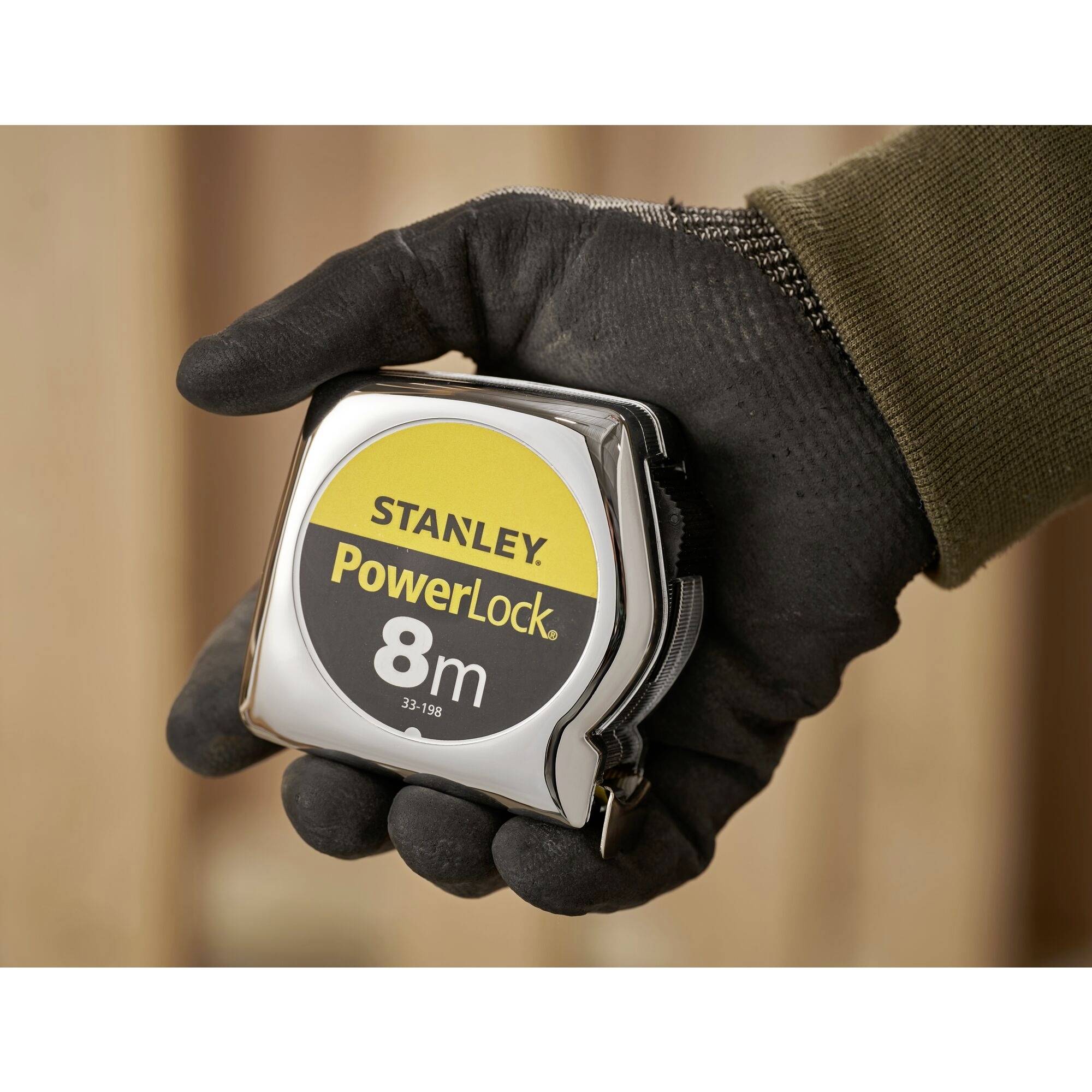 En hånd holder et målebånd fra mærket Stanley, model PowerLock, med en længde på 8 meter.
