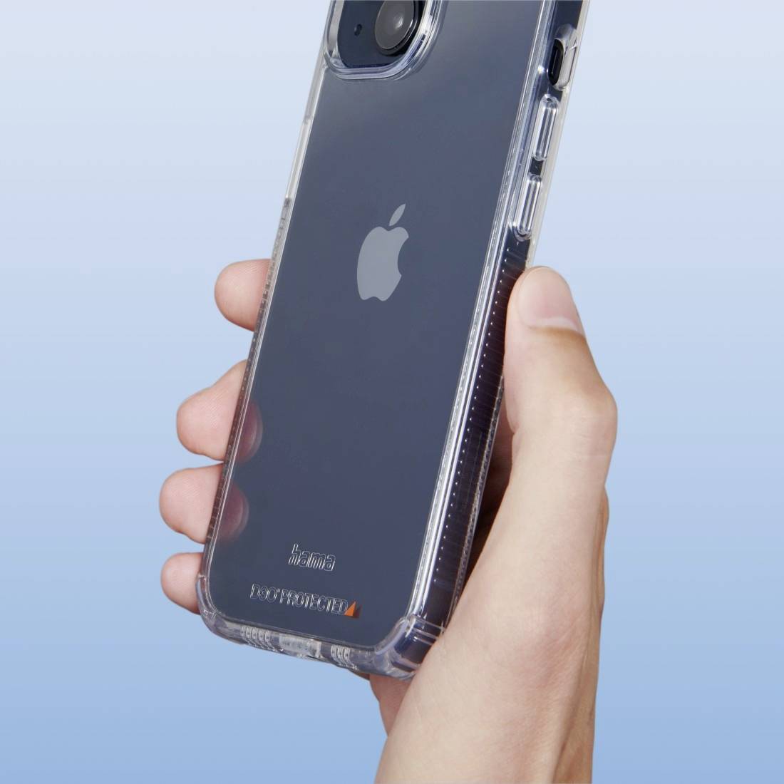 En hånd holder en smartphone med et gennemsigtigt beskyttelsescover, bagsiden viser et Apple-logo. Baggrunden er blå.