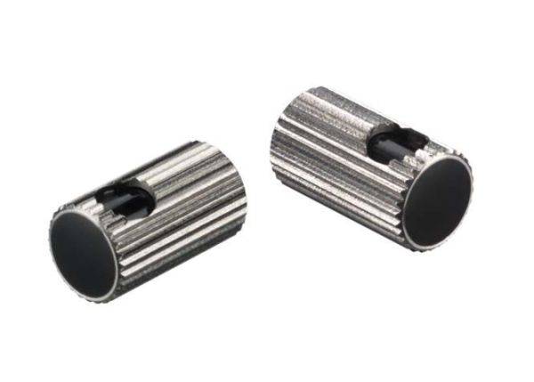 To drejelige sølvfarvede cylindriske metalstykker med riflet overflade, hver med en sort plastikkerne i midten.