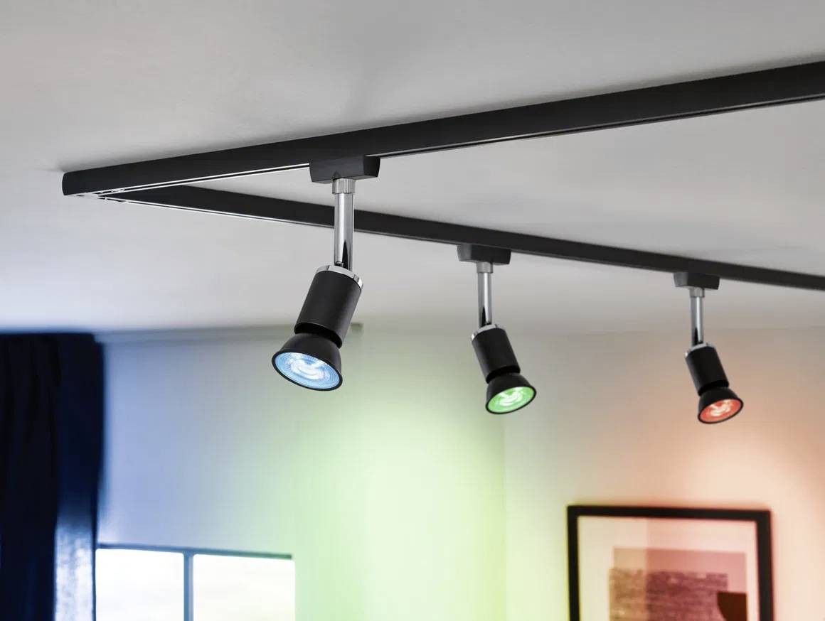 Tredobbelt LED-spotlampe i sort med farverige lyseffekter i loftet i et rum, belyst i blå, grøn og rød.