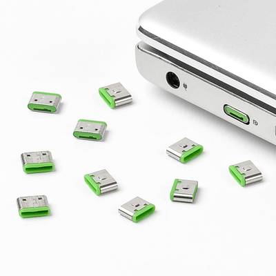 Bærbar computer med magnetiske USB-stikadaptere, markeret med grønt. Adaptere spredt rundt omkring. Fokus på nem tilslutning.