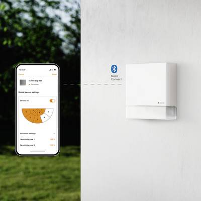 Smartphone viser termostat-styrings-app ved siden af hvid vægtermostat. Forbundet via Bluetooth Mesh.