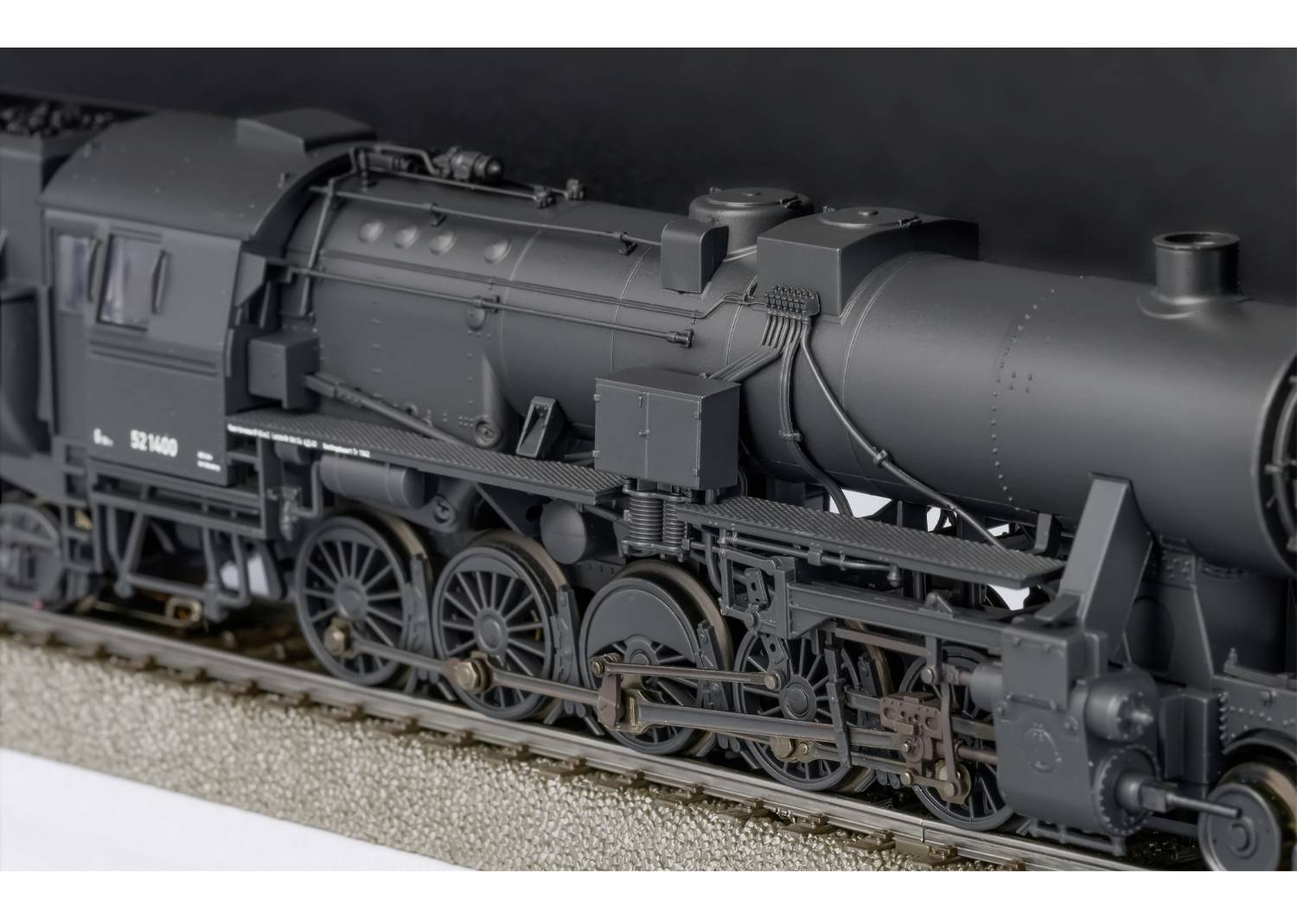 En detaljeret model af et damplokomotiv set tæt på, sort, med synlige hjul og komplekse mekaniske dele.